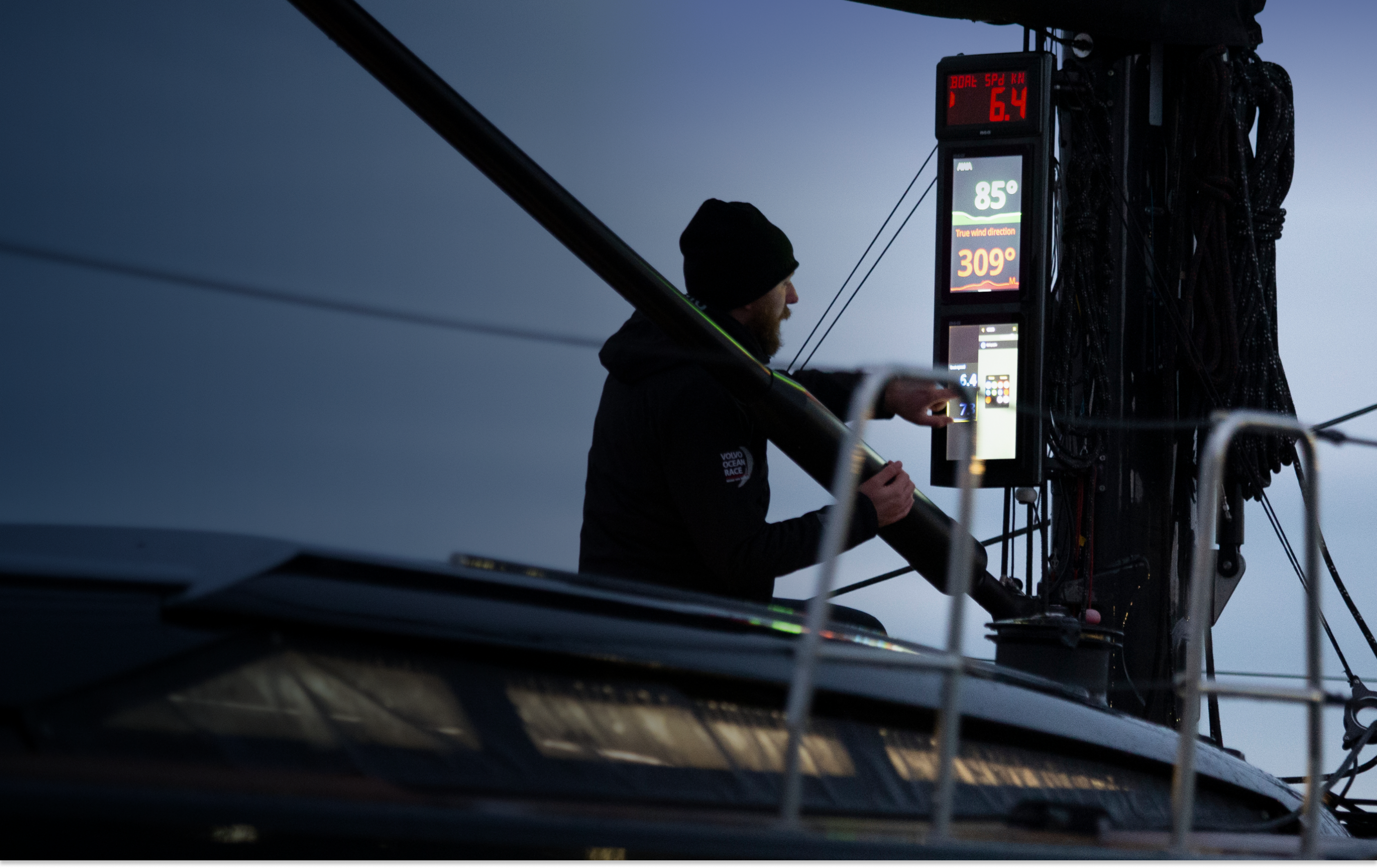 A man using sailing electronics and instruments to check data while on a sailboat. 